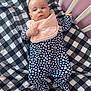 baby, crib, blanket, onesie, heart_pattern, pink_bib, infant, sleepwear, bed, child, furniture, resting, indoor, cute, person, soft_toys, sleeping_area, baby_garment, comfort, nursery