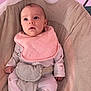 baby, infant, pink_bib, baby_seat, cozy, pastel_colors, newborn, soft_fabric, cute, indoor, child, portrait, small_hands, sleepwear, comfort, seated, looking_up, young_child, face, peaceful