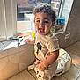 Kyle a rejoint le concours — aidez-le/la à gagner de superbes lots ! bag, black_shoes, child, curly_hair, footwear, happy, indoor, kitchen, mickey_mouse, person, reflection, shirt, shorts, smiling, sunlight, tile_floor, toddler, toy, white_bag, window