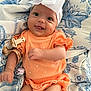 baby, infant, child, orange_outfit, headband, bow, blanket, pattern, blue, white, smiling, tongue_out, cute, happy, lying_down, fabric, clothing, soft_toys, pacifier, person