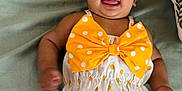 Zaifa is registered to the contest to win money with this photo: baby, infant, child, polka_dot, bow, headband, milestone, 4_months, smiling, tongue_out, cute, lying_down, blanket, flower_sign, orange, white, happy, celebration, portrait, playful