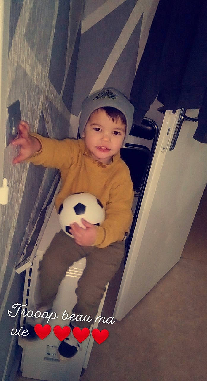 Ismaël participe au concours pour gagner de l'argent avec cette photo : ball, baseball_cap, child, cool, eye, flash_photography, flooring, football, fun, happy, hat, headwear, human_body, panda, person, personal_protective_equipment, smile, soccer_ball, teddy_bear, toddler