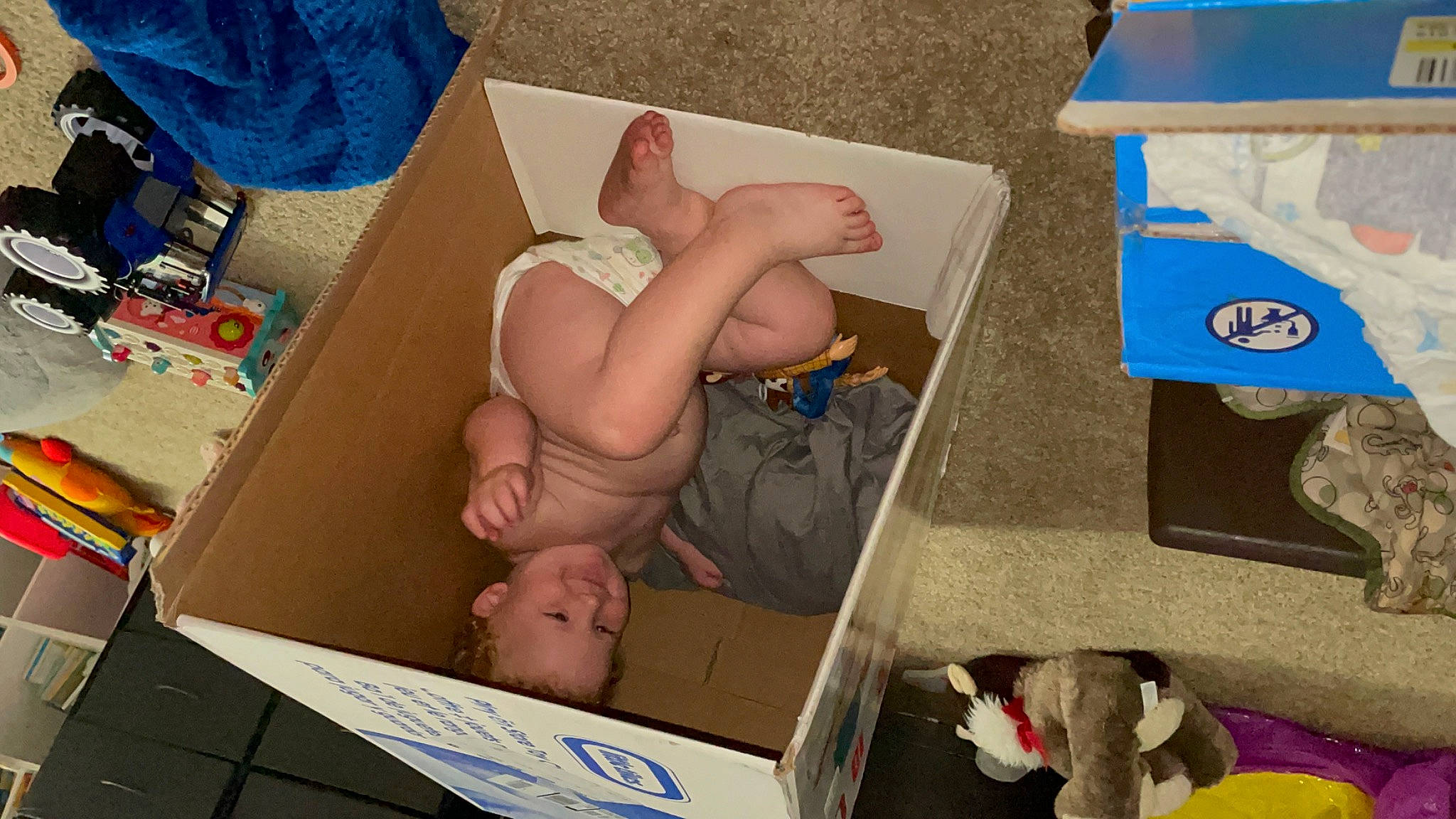 Russell is registered to the contest to win money with this photo: abdomen, art, baby, baby_products, barechested, blue, chest, child, comfort, diaper, foot, human_body, human_leg, joy, person, room, shipping_box, thigh, toddler, toy