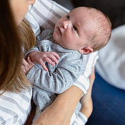 Maë participe au concours pour gagner de l'argent avec cette photo : baby, newborn, infant, mother, holding, embrace, face, skin, clothing, striped_shirt, gray_outfit, hand, arm, person, indoor, love, tenderness, portrait, closeup, family