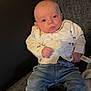 baby, infant, child, couch, clothing, jeans, shirt, sneakers, footwear, indoor, person, face, head, expression, cute, young, seated, blanket, home, casual