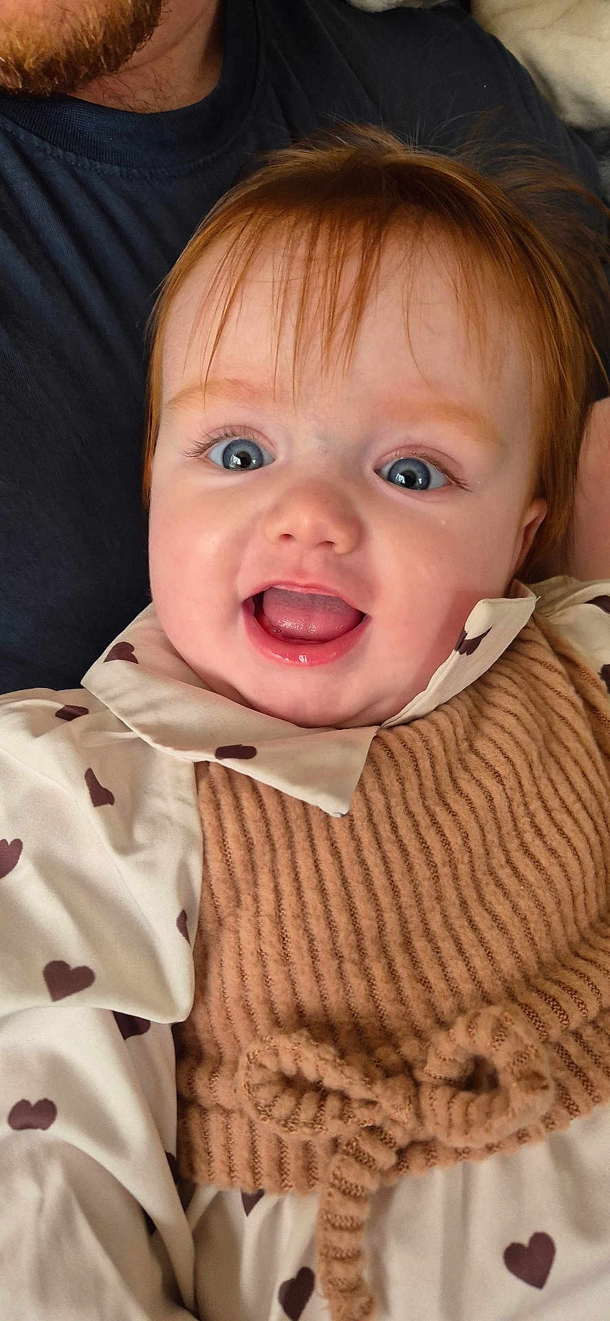 Oxana a rejoint le concours — aidez-le/la à gagner de superbes lots ! baby, child, smiling, happy, face, blue_eyes, red_hair, knitted_bib, heart_pattern, clothing, portrait, close_up, cute, infant, person, apparel, warm, indoor, adult_arm, joyful