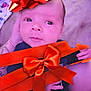 baby, infant, face, hand, red_bow, ribbon, gift_wrap, person, skin, clothing, tattoo, holding, closeup, cute, newborn, portrait, indoors, soft_lighting, expression, celebration