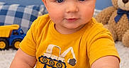 Asher is registered to the contest to win money with this photo: baby, child, infant, portrait, sitting, smiling, blue_eyes, blond_hair, yellow_shirt, construction_shirt, toy_truck, teddy_bear, playroom, indoor, carpet, cushion, stars, blue_background, birthday_milestone, close_up
