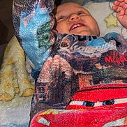 Kaëlan a rejoint le concours — aidez-le/la à gagner de superbes lots ! baby, child, smiling, fleece, blanket, cartoon, red_car, clothing, cute, indoor, cozy, happy, raising_arm, person, face, fuzzy, soft, playful, toddler, comfort