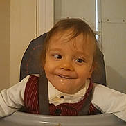 Tiago participe au concours pour gagner de l'argent avec cette photo : toddler, child, high_chair, smile, happy, clothing, vest, white_shirt, face, indoors, messy, drool, food, seat, person, baby, cute, expression, young, sitting