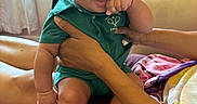 Jy Len is registered to the contest to win money with this photo: baby, child, smiling, curly_hair, indoor, person, hands, holding, couch, window, curtains, plush_toy, phone, purple, green_clothing, legs, feet, happy, portrait, family