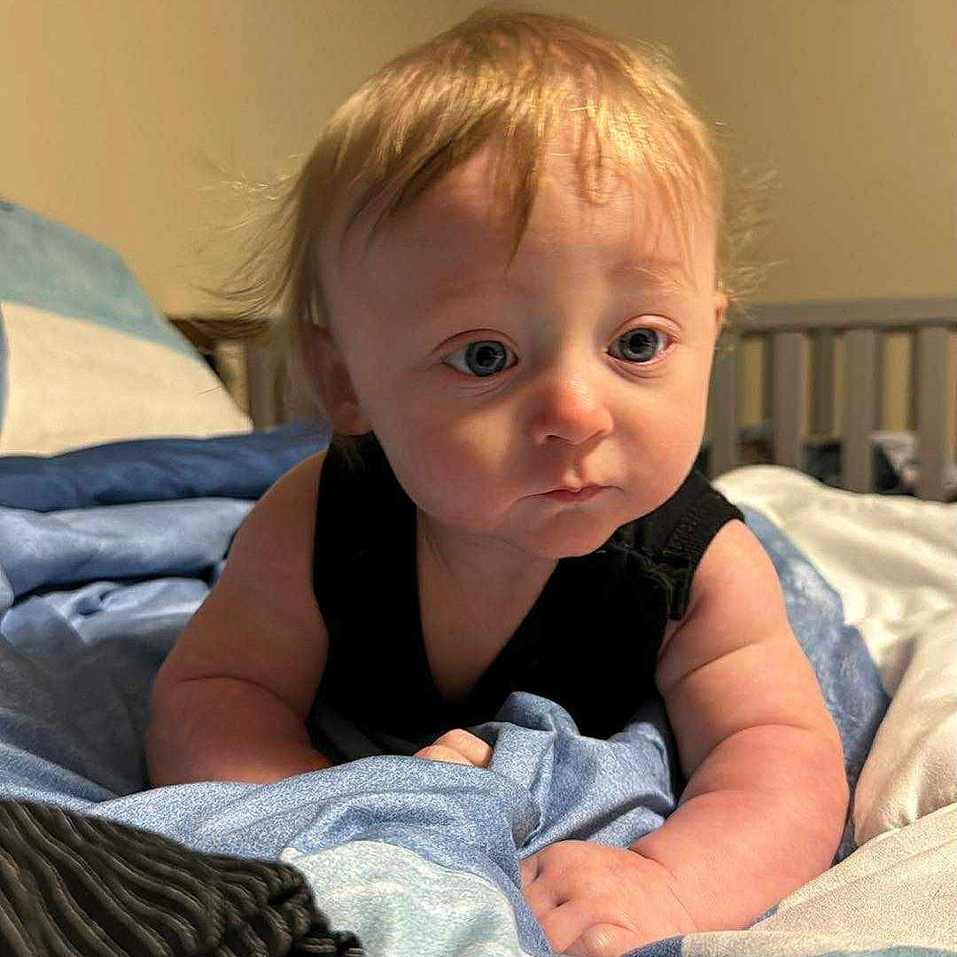 Jordon is registered to the contest to win money with this photo: baby, bed, blanket, blue_eyes, child, curly_hair, cute, expression, hand, indoor, infant, lying_down, nursery, person, portrait, skin, sleepwear, soft_lighting, toddler, young