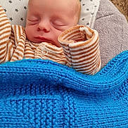 Ian a rejoint le concours — aidez-le/la à gagner de superbes lots ! baby, newborn, sleeping, blanket, pajamas, striped_clothing, pillow, stars_pattern, cozy, soft, cushion, infant, resting, indoors, child, peaceful, cute, portrait, knit_blanket, sleep