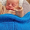 baby, newborn, sleeping, blanket, pajamas, striped_clothing, pillow, stars_pattern, cozy, soft, cushion, infant, resting, indoors, child, peaceful, cute, portrait, knit_blanket, sleep