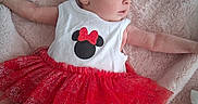 Azriella is registered to the contest to win money with this photo: baby, infant, tutu_skirt, red_skirt, white_top, minnie_mouse, soft_blanket, lying_down, blue_eyes, socks, cute, child, portrait, indoors, fabric, texture, clothing, baby_girl, soft_lighting, curious
