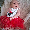 baby, infant, child, tutu, red_skirt, white_top, minnie_mouse, blue_eyes, fluffy_blanket, pink_blanket, cute, clothing, laying_down, portrait, indoor, soft_texture, small_hand, gaze, newborn, person