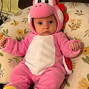Azriella is registered to the contest to win money with this photo: baby, child, pink_costume, dinosaur_costume, plush, cute, infant, face, eyes, cushion, floral_pattern, indoors, seated, clothing, hooded_outfit, expression, fist, soft_toy, costume, portrait
