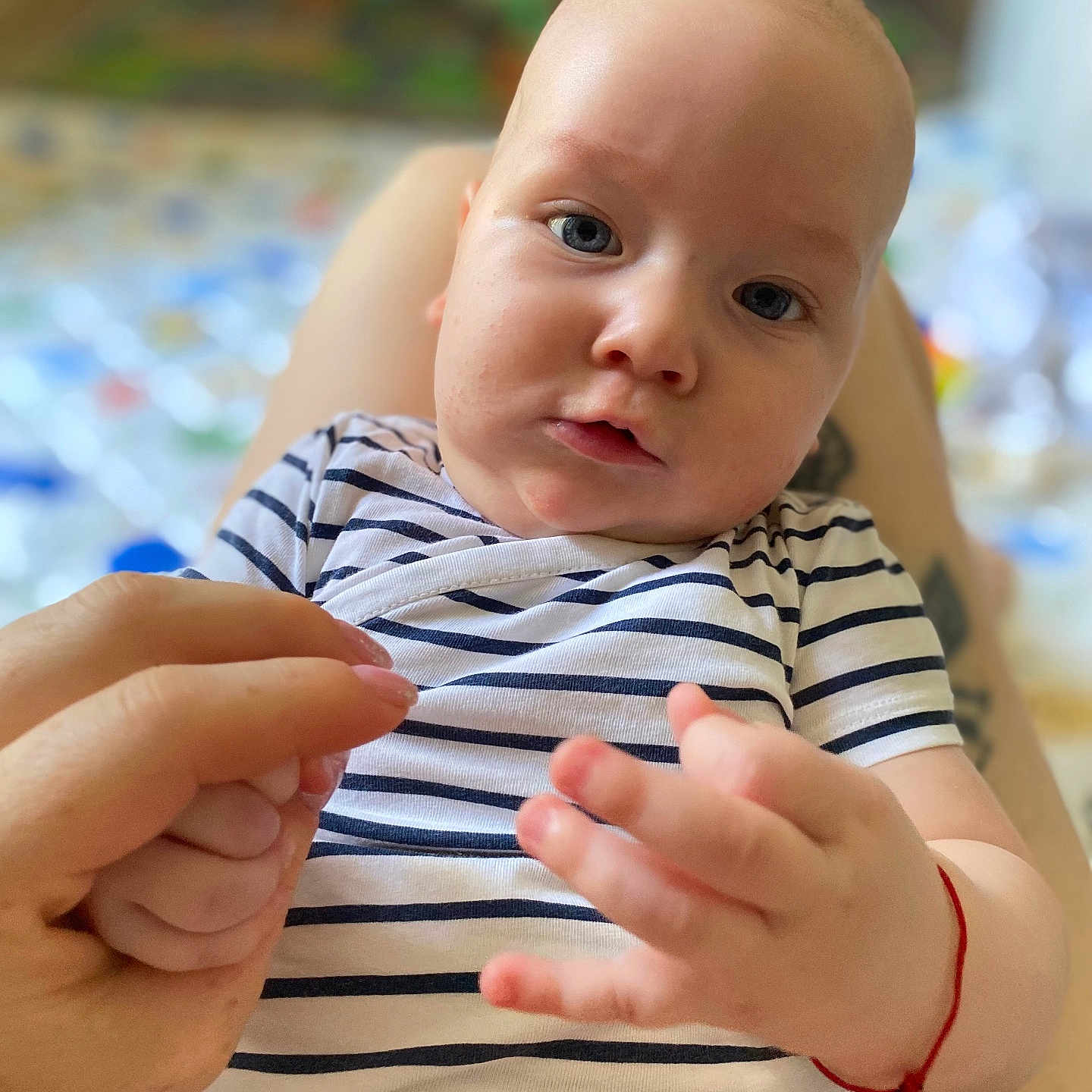 Vladimir a rejoint le concours — aidez-le/la à gagner de superbes lots ! adult_hand, baby, blue_eyes, blurred_background, casual_clothing, child, close_up, cute, expression, fingers, hand, indoor, infant, intimate_moment, person, portrait, skin, soft_light, striped_shirt, young