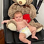 baby, diaper, teddy_bear, plush_toy, black_chair, heart, indoor, wooden_floor, relaxed, cute, child, infant, soft_toy, furniture, smiling, person, skin, comfort, seated, toy