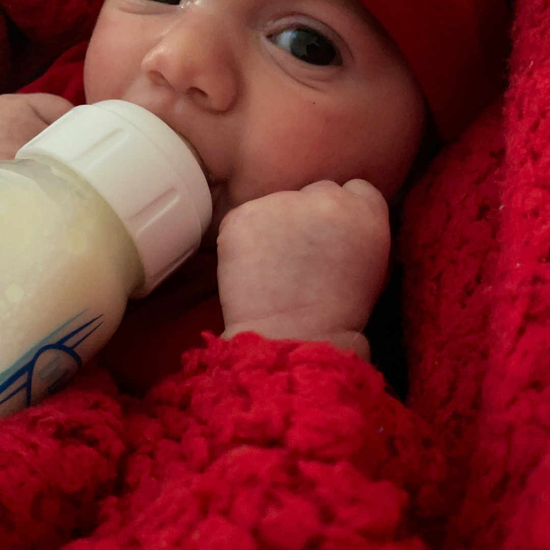 Azaiah joined the competition — help win amazing prizes! baby, blanket, bottle, child, closeup, cozy, cute, face, feeding, hand, hat, infant, knit, milk, newborn, person, portrait, red, soft, warm
