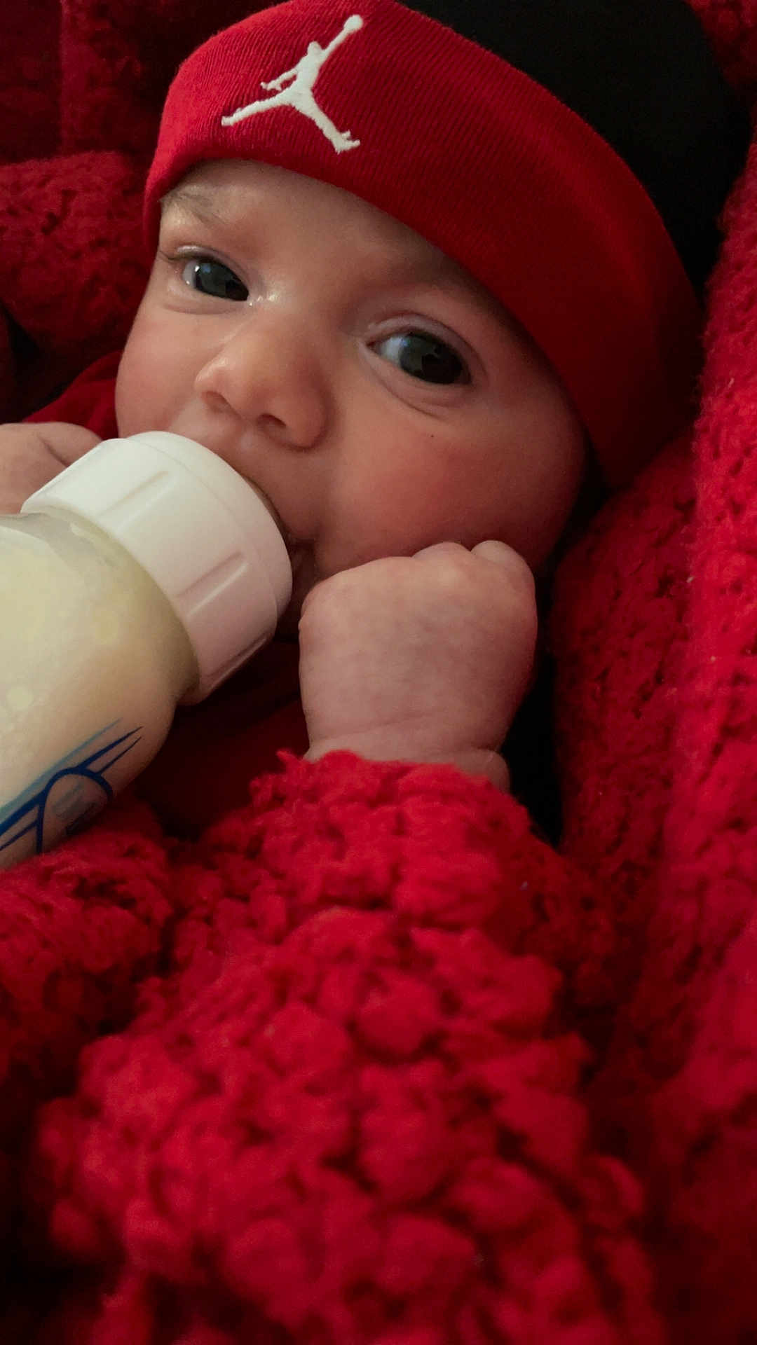 Azaiah joined the competition — help win amazing prizes! baby, bottle, milk, red, knit, blanket, hat, face, hand, infant, closeup, cute, child, warm, cozy, feeding, person, newborn, soft, portrait
