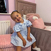 Isabella-Rose joined the competition — help win amazing prizes! bedroom, blue_dress, carpet, child, cute, furniture, girl, happy, headboard, home, indoors, pink_ottoman, plush_pillow, portrait, radiator, sitting, smiling, sock, toy, window