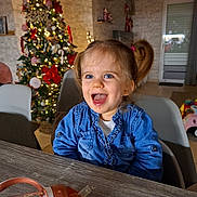 Mélina a rejoint le concours — aidez-le/la à gagner de superbes lots ! toddler, child, smiling, denim_shirt, pigtails, christmas_tree, holiday_decor, indoor, table, cup, happy, face, person, festive, home, lights, decorations, joyful, seated, playroom