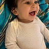 baby, child, smiling, white_onesie, curly_hair, towel, blue, striped, happy, infant, lying_down, portrait, cute, skin, face, small_hands, indoors, cozy, expression, young