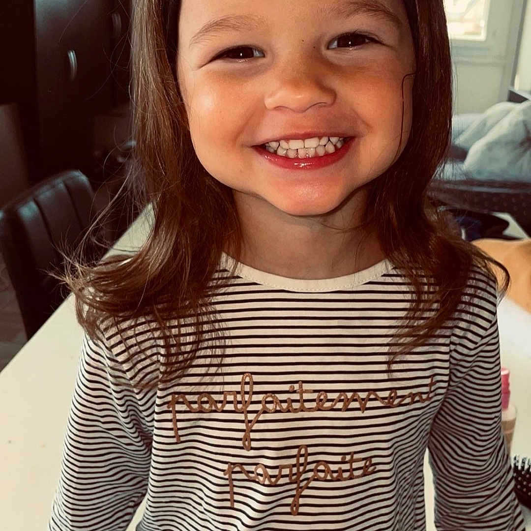 Thaïs participe au concours pour gagner de l'argent avec cette photo : blouse, bodypart, child, clothing, face, female, girl, happy, head, indoors, longsleeve, mouth, pants, person, photography, portrait, sleeve, smile, t_shirt, teeth