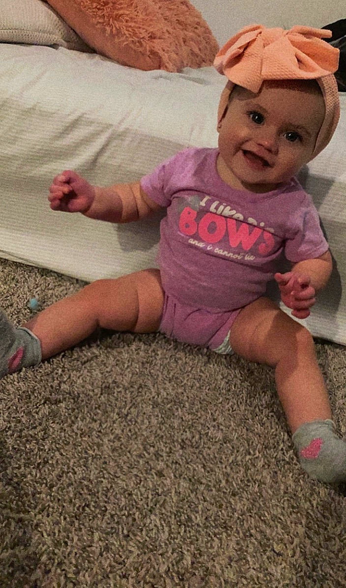 Heavenly is registered to the contest to win money with this photo: baby, baby_toddler_clothing, baseball_cap, cap, eye, floor, flooring, foot, fun, grass, happy, human_leg, joy, knee, person, pink, skin, sleeve, smile, t_shirt