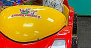 Chase joined the competition — help win amazing prizes! child, glasses, smile, indoor, play_area, arcade, ride, car, toy, red, yellow, cartoon_mouse, amusement, fun, entertainment, clothing, person, happy, playground, kid