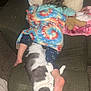 child, cat, blanket, chair, cushion, carpet, foot, sleeping, resting, indoor, furniture, cozy, home, nap, pet, animal, toddler, colorful, tie_dye, relaxation