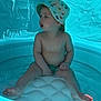 toddler, child, inflatable_pool, bucket_hat, dinosaur_pattern, water, summer, blue, canopy, bare_chest, sitting, foot, hand, expression, indoors, play, cute, young_child, plastic, relaxation