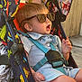 animal_print, baby, baby_stroller, casual, child, clothing, colorful, cute, expression, outdoor, person, playful, seat, seatbelt, stroller, summer, sunglasses, sunlight, toddler, wooden_deck