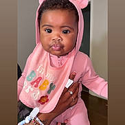 Katori joined the competition — help win amazing prizes! baby, child, pink_clothing, hood, bib, tattoo, bracelets, hand, indoor, person, cute, face, eyes, lips, holding, infant, apparel, portrait, expression, room