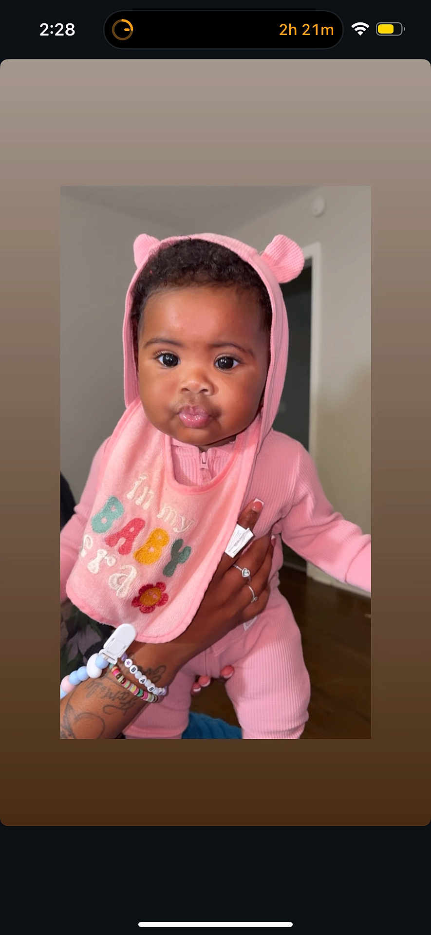 Katori joined the competition — help win amazing prizes! baby, child, pink_clothing, hood, bib, tattoo, bracelets, hand, indoor, person, cute, face, eyes, lips, holding, infant, apparel, portrait, expression, room