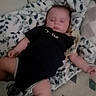 baby, infant, sleeping, face, portrait, black_outfit, blanket, bed, bedding, patterned_fabric, leaf_pattern, indoors, lying_down, arms, legs, peaceful, cozy, home, photograph, timestamp