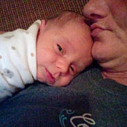 John is registered to the contest to win money with this photo: newborn, baby, infant, child, adult, parent, cuddling, portrait, close_up, face, sleepy, lying_down, blanket, onesie, indoor, family, affection, tenderness, warmth, photograph