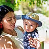 Camilo joined the competition — help win amazing prizes! baby, casual_clothing, child, cute, daylight, family, greenery, happy, hat, holding, mother, nature, outdoor, person, portrait, shadow, smile, sun_hat, sunlight, woman
