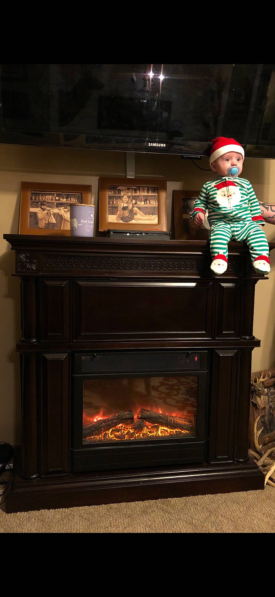 Hunter is registered to the contest to win money with this photo: christmas, christmas_eve, christmas_stocking, fire_screen, fireplace, gas, headwear, hearth, heat, holiday, home, person, room, stove, wood, wood_burning_stove