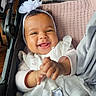 baby, smiling, child, headband, flower, stroller, white_clothing, blanket, happy, infant, cute, hands, portrait, indoors, seat, baby_girl, clapping, soft_light, closeup, comfortable