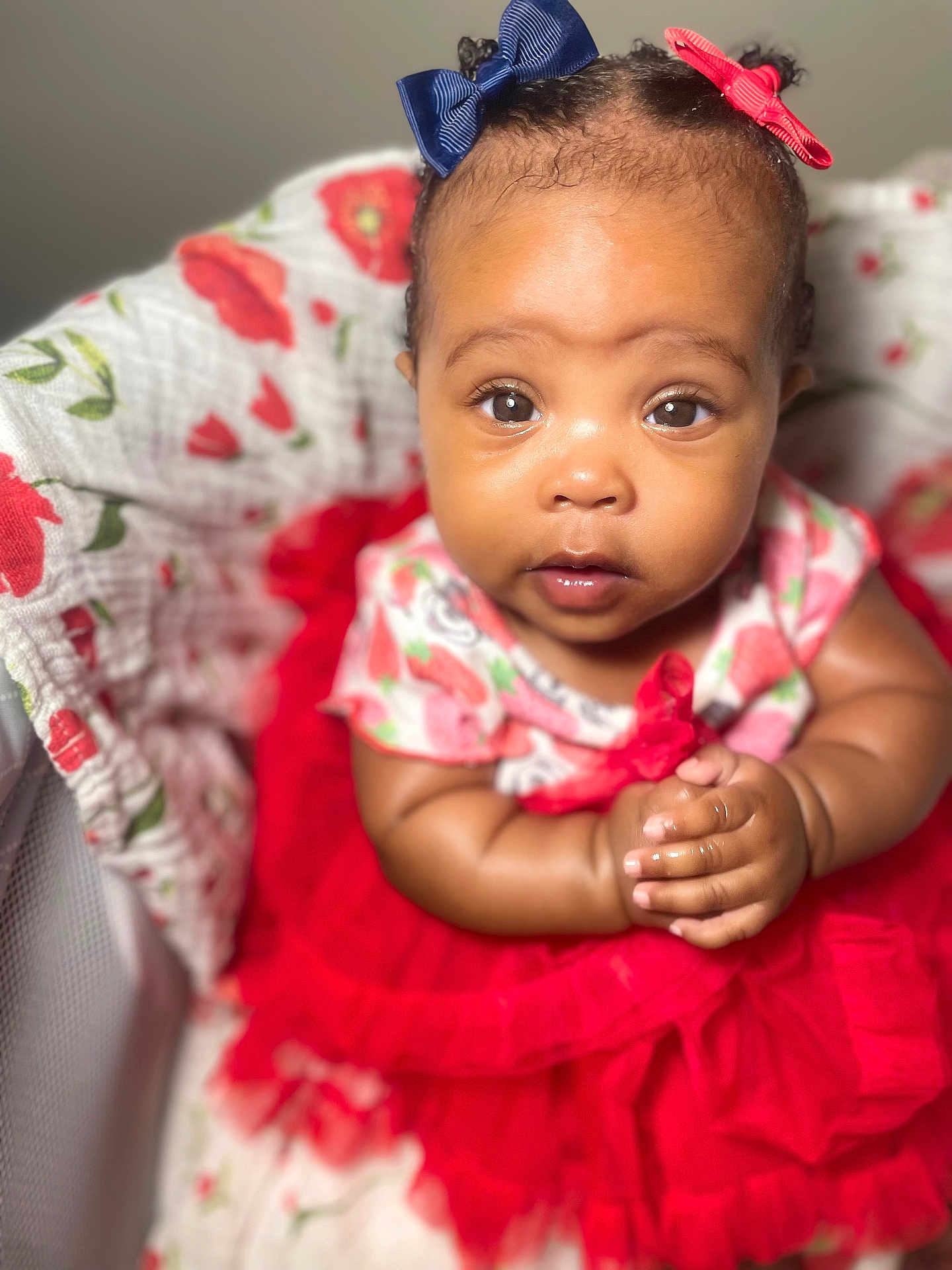 Myaria is registered to the contest to win money with this photo: adorable, baby, bassinet, bows, child, close_up, curious_expression, cute, floral_pattern, hair_bows, hands_clasped, indoors, infant, portrait, red_dress, sitting, soft_lighting, tutu, wide_eyes, young_child