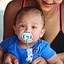 baby, pacifier, blue_shirt, adult, holding, smile, closeup, face, person, child, cute, toddler, earrings, skin, hand, parent, bonding, indoor, portrait, love