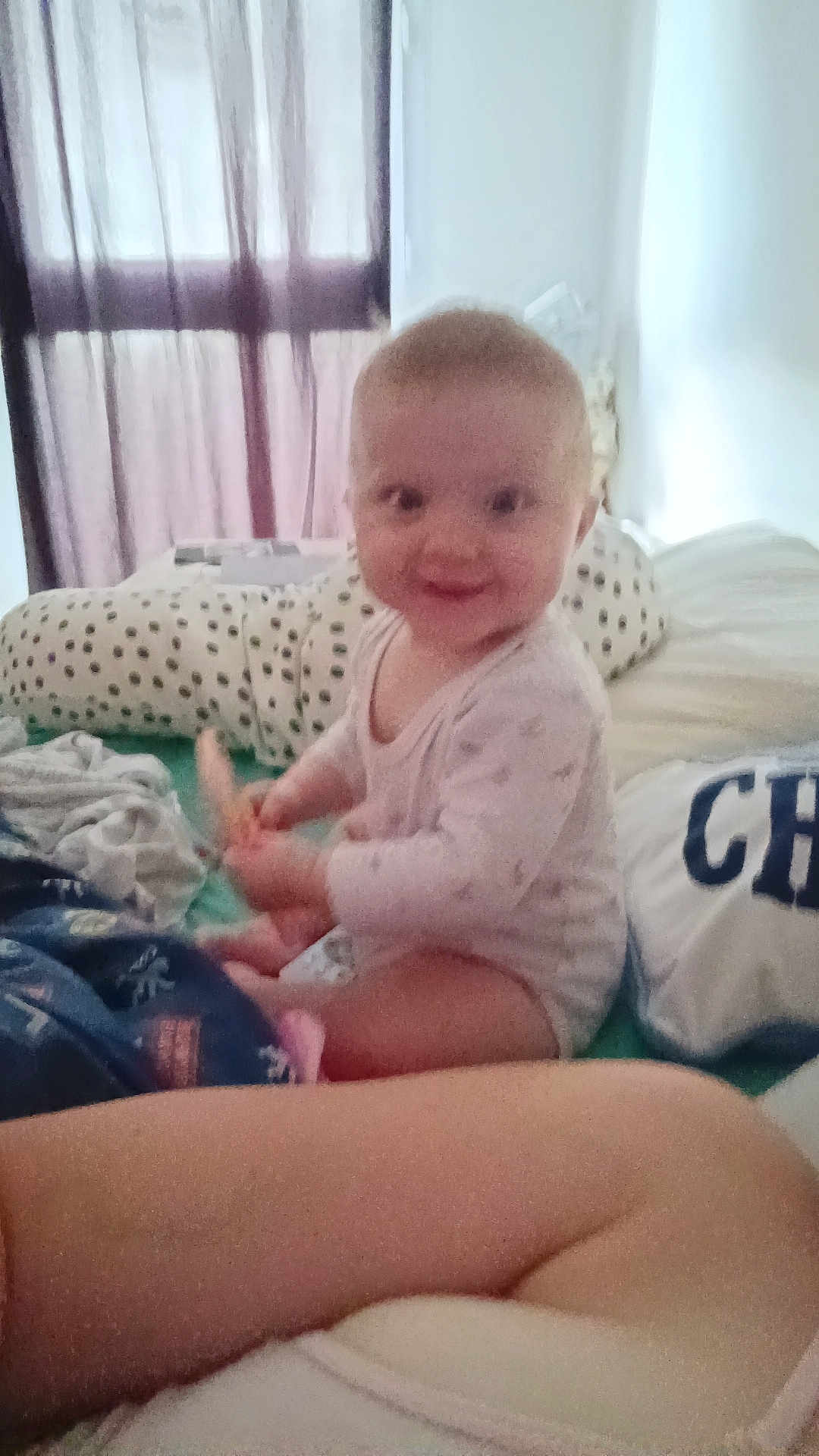 Eliana participe au concours pour gagner de l'argent avec cette photo : baby, child, smiling, indoor, bed, pillow, blanket, window, curtain, clothing, person, infant, cute, playful, home, soft_light, relaxed, seated, happy, young