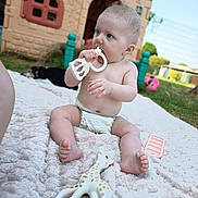 Eliana a rejoint le concours — aidez-le/la à gagner de superbes lots ! baby, child, teething_toy, giraffe_toy, blanket, diaper, outdoor, grass, dog, playhouse, fence, toy, sunny, blue_sky, garden, foot, hand, face, curious, sitting