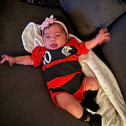 Lara joined the competition — help win amazing prizes! baby, infant, blanket, couch, remote_control, headband, clothing, socks, person, indoor, lying_down, cute, smiling, arm, leg, soft_fabric, comfort, resting, home, portrait