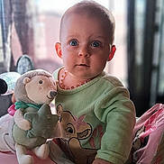 𝑇𝑦𝑎𝑛𝑎 participe au concours pour gagner de l'argent avec cette photo : baby, child, plush_toy, hedgehog, onesie, green_clothing, necklace, baby_chair, indoor, window, curious_expression, soft_toy, infant, portrait, hand, cute, seated, daylight, face, person