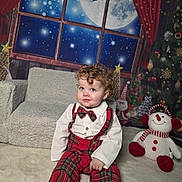 Harrison is registered to the contest to win money with this photo: bow_tie, carpet, child, christmas_tree, cozy, curly_hair, curtain, festive, holiday_decor, indoors, moon, plush_toy, red_plaid, sitting, smiling, snowman, suspenders, toddler, white_shirt, window