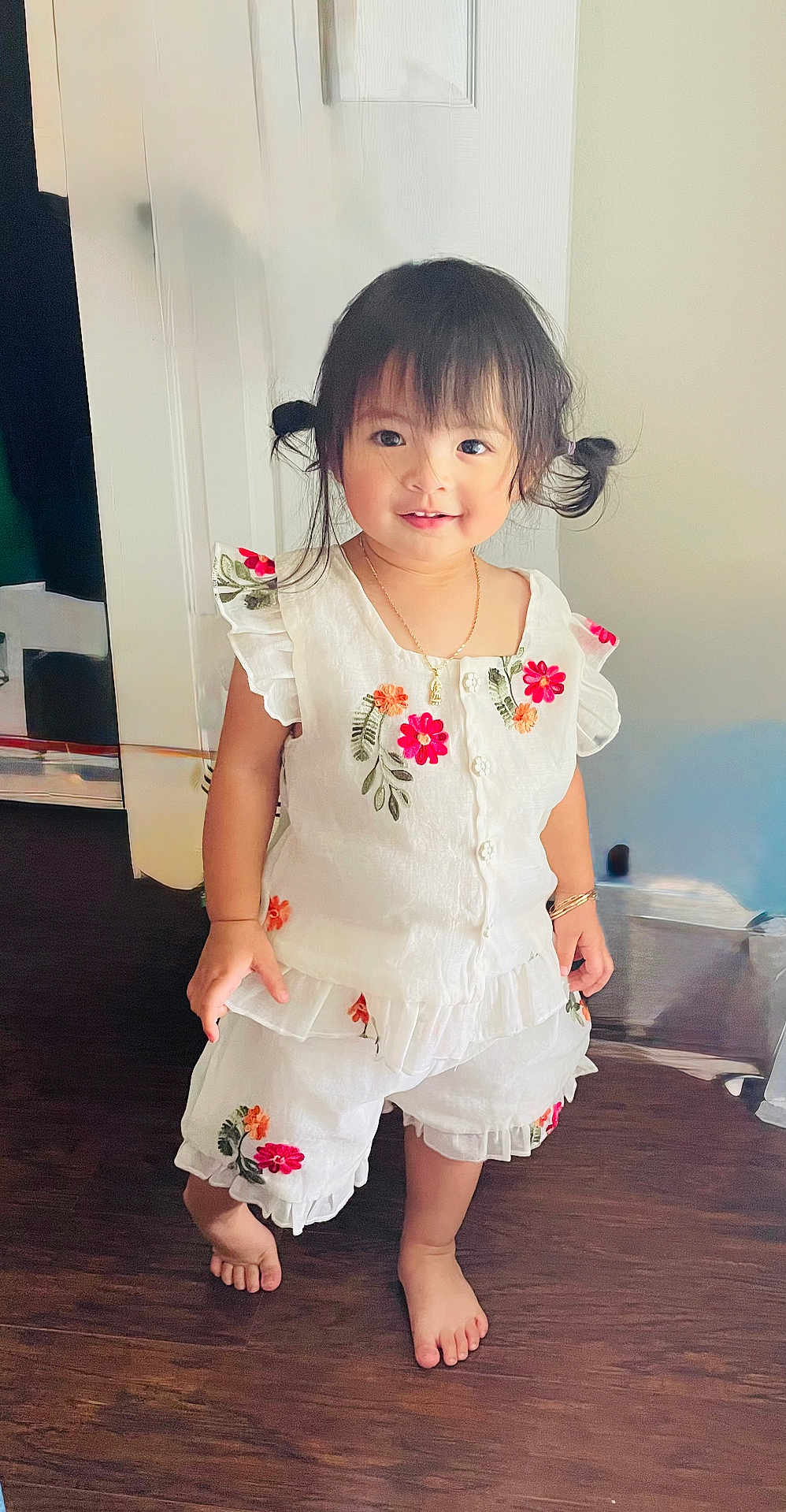 Katie joined the competition — help win amazing prizes! toddler, child, girl, pigtails, barefoot, white_outfit, floral_embroidery, standing, wooden_floor, indoor, smiling, cute, jewelry, necklace, bracelet, shorts, ruffles, portrait, happy, young_child