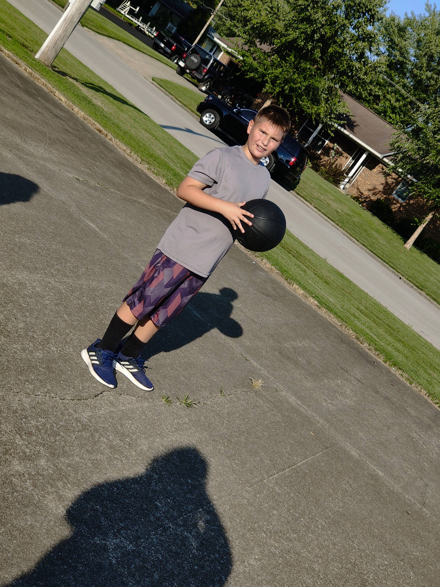 Michael is registered to the contest to win money with this photo: asphalt, automotive_wheel_system, fun, grass, knee, leisure, person, physical_fitness, plant, recreation, road, road_surface, rolling, shorts, sidewalk, sports, street_stunts, t_shirt, tire, tree